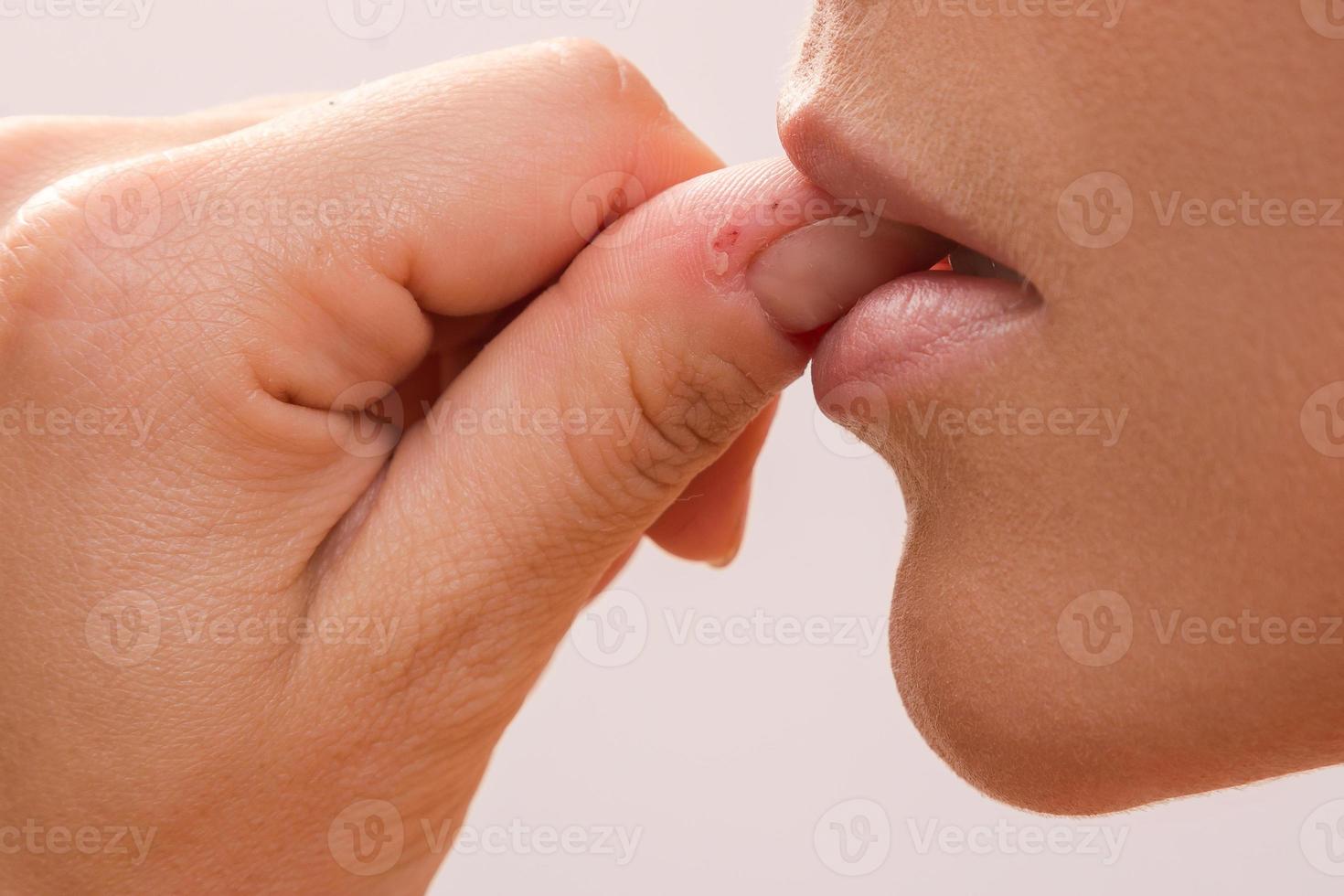 Closeup of a female mouth biting her fingers photo