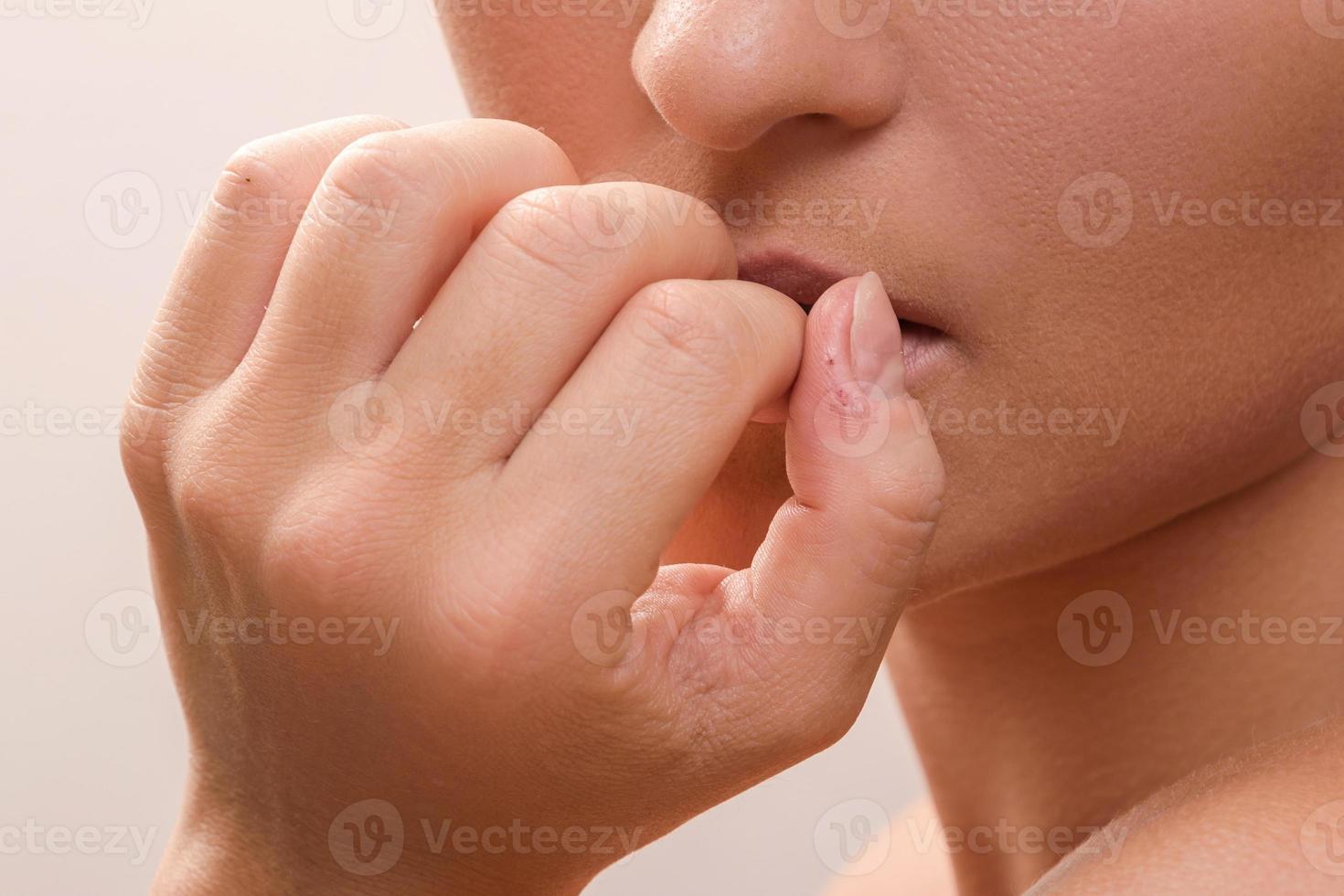 Closeup of a female mouth biting her fingers photo