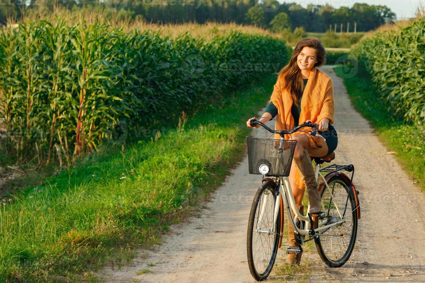 la mujer va en bicicleta por la carretera rural en el maizal foto