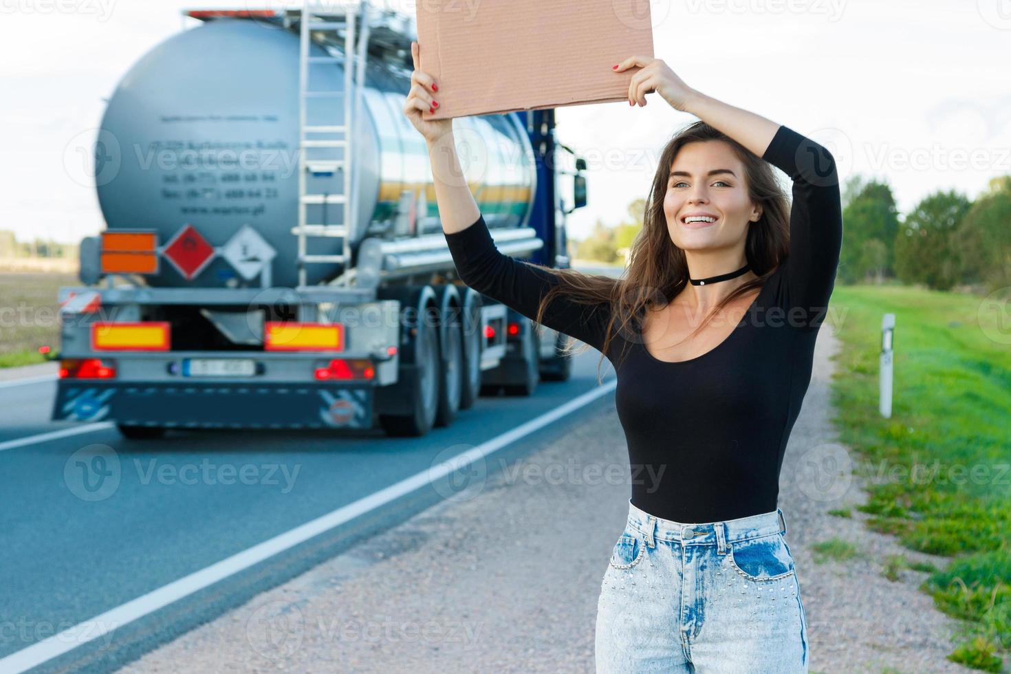 autostopista en la carretera tiene un cartel de cartón en blanco foto