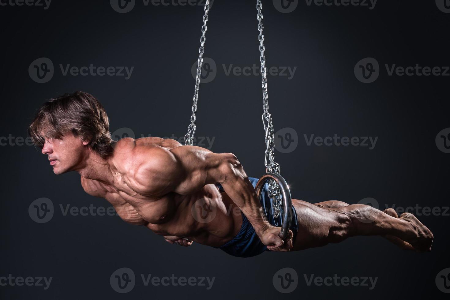 Strong and muscular gymnast guy on the rings photo