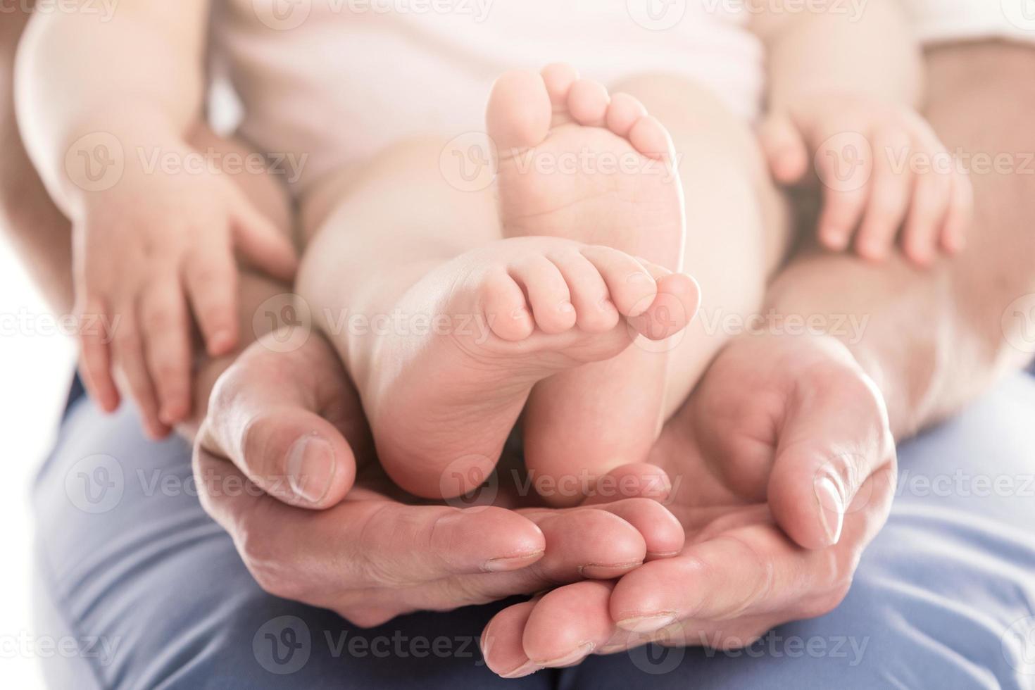 manos del padre sosteniendo los pies de su bebé foto