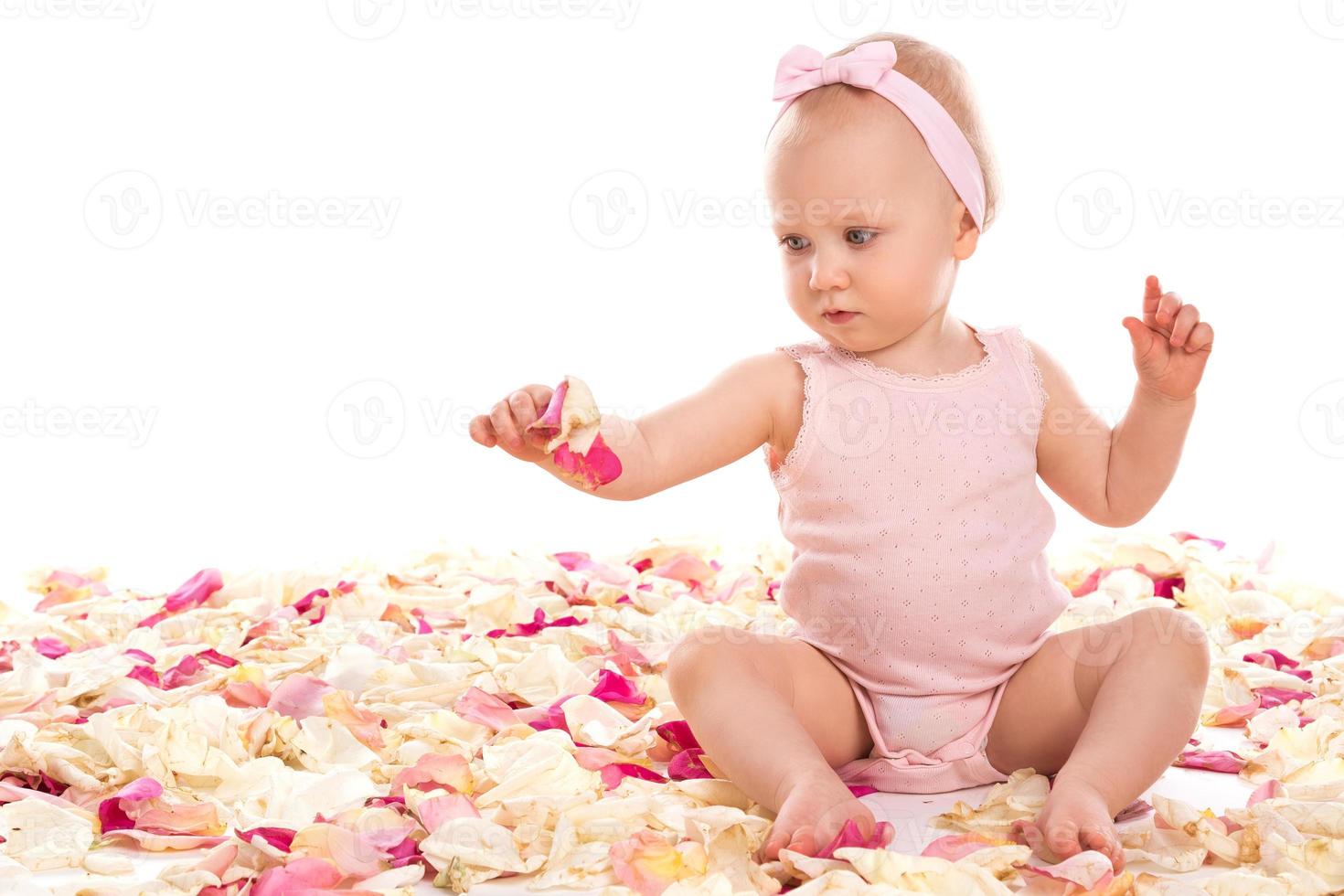 Cute baby girl sitting surrounded rose petals photo