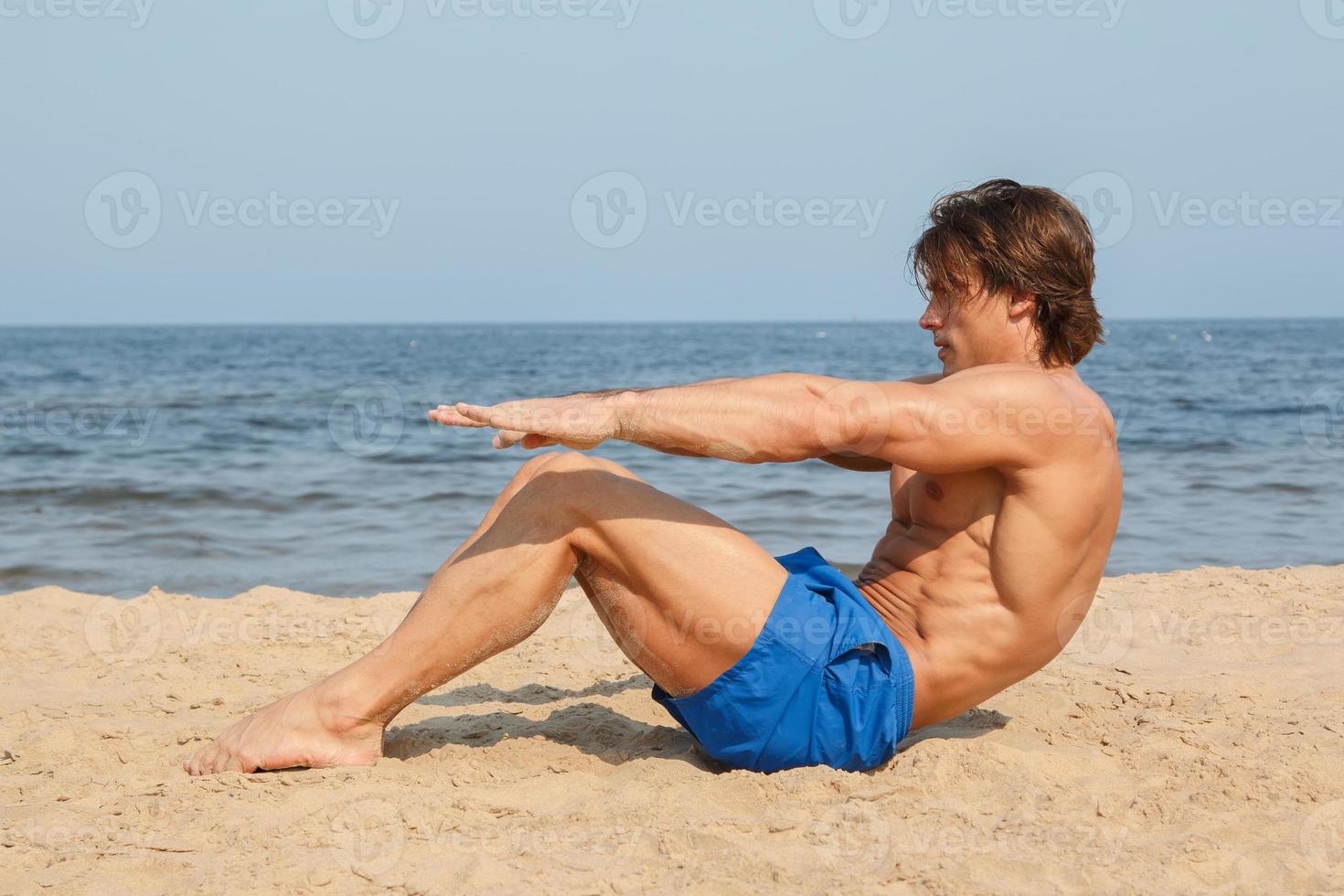 Muscular man during his workout on the beach photo