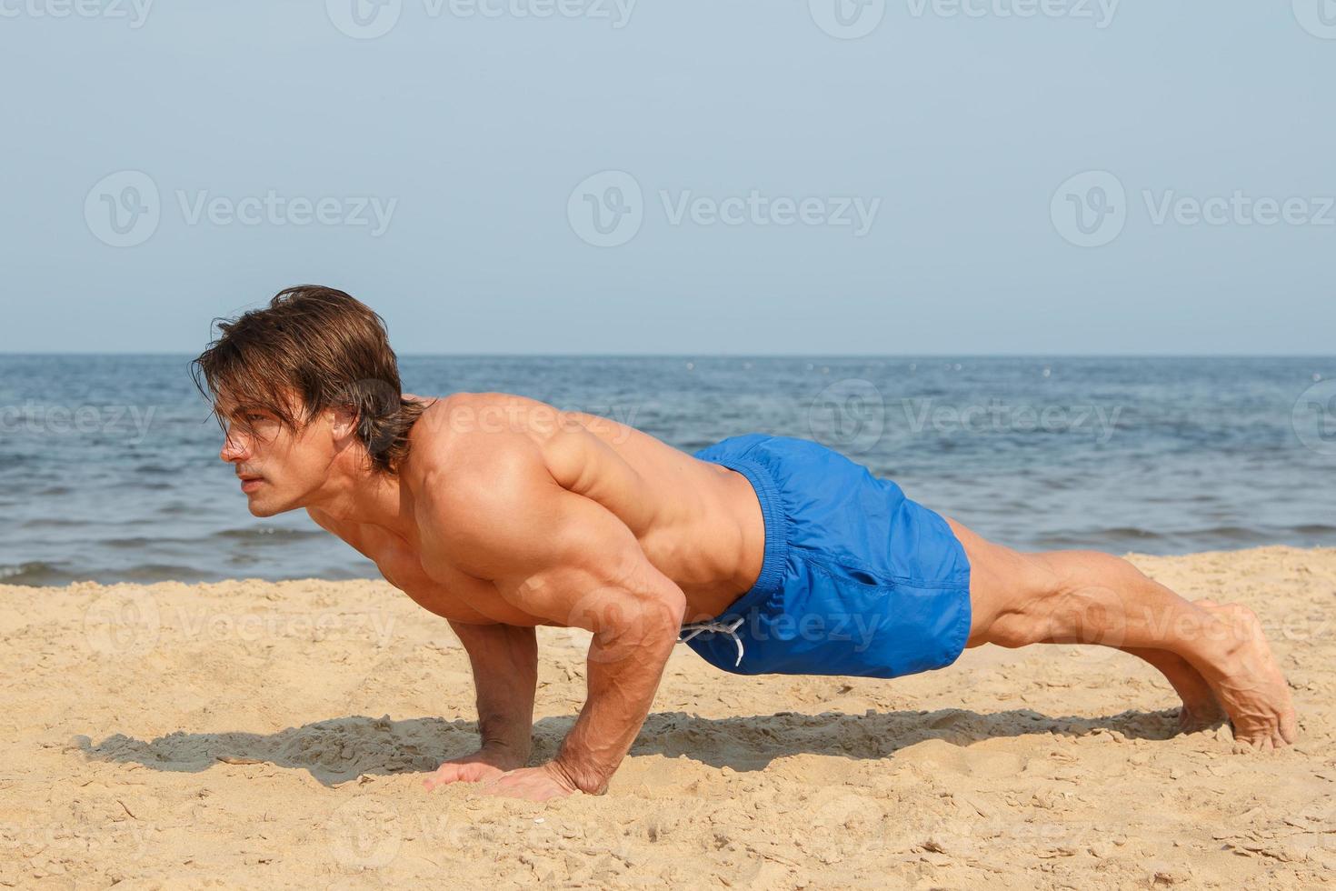 Muscular man during his workout on the beach photo