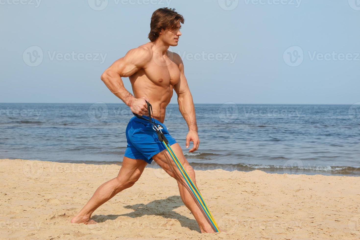 Guy working out with rubber band on the beach photo