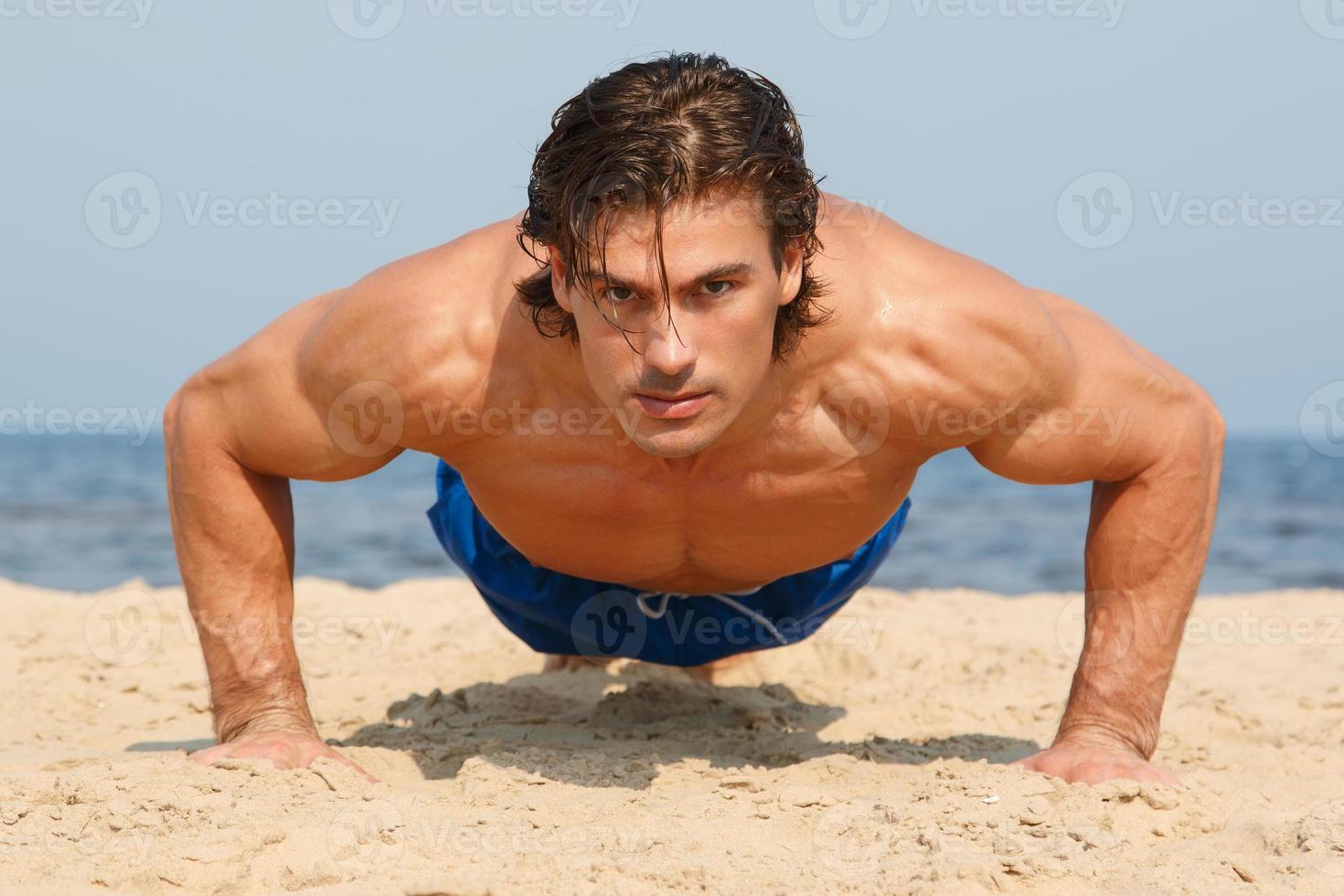 Muscular man during his workout on the beach photo