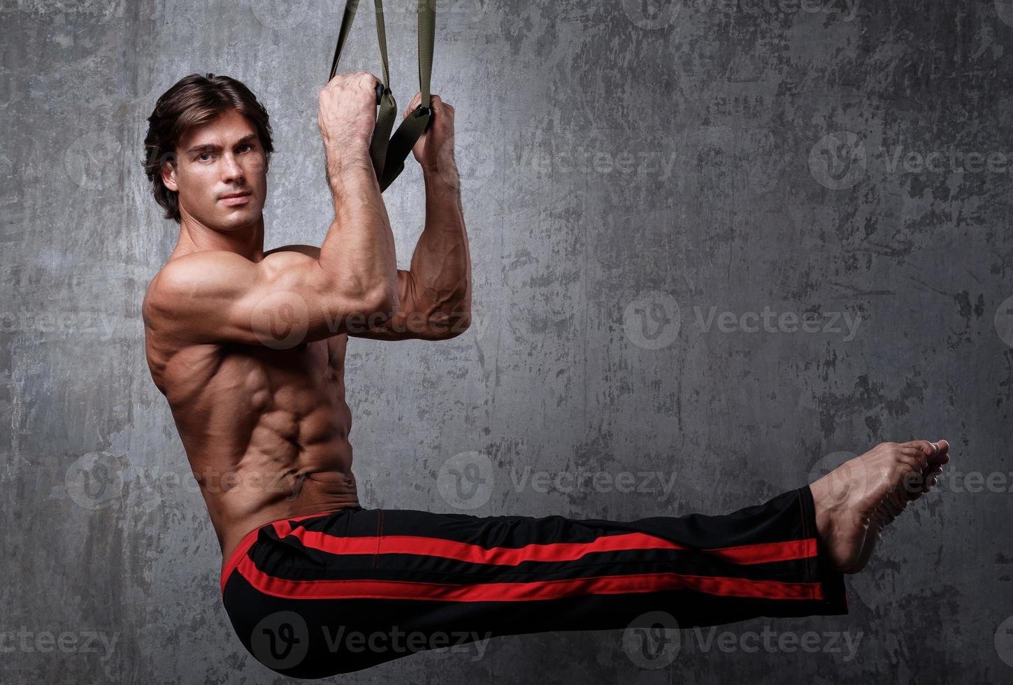 Muscular man during workout with suspension straps photo