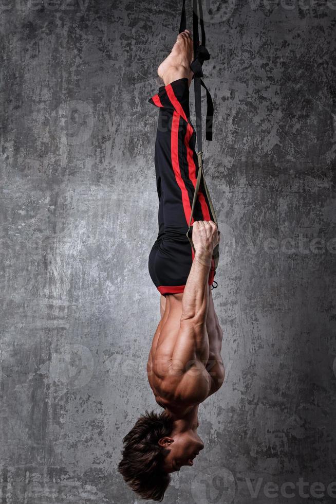 Muscular man during workout with suspension straps photo