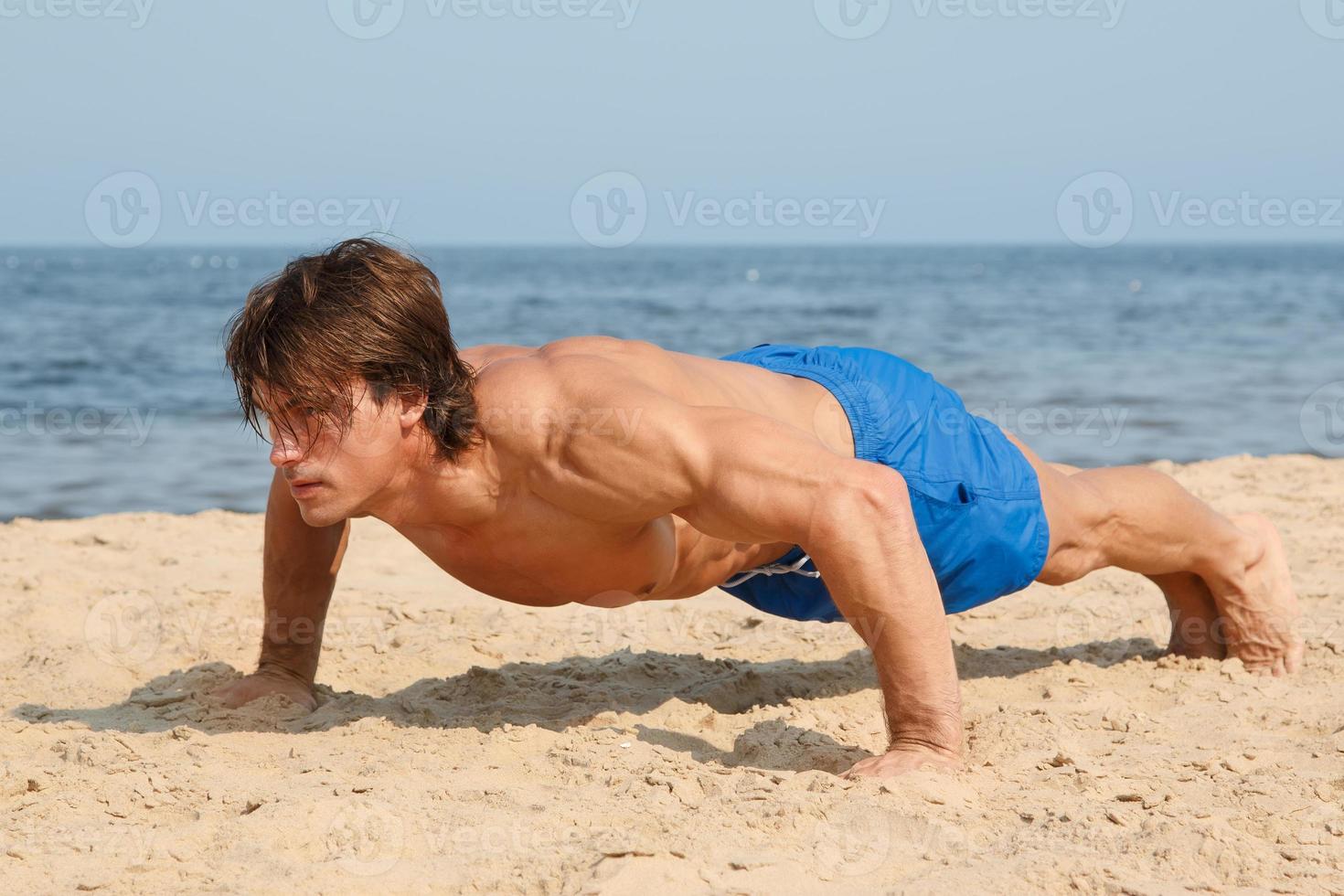 Muscular man during his workout on the beach photo