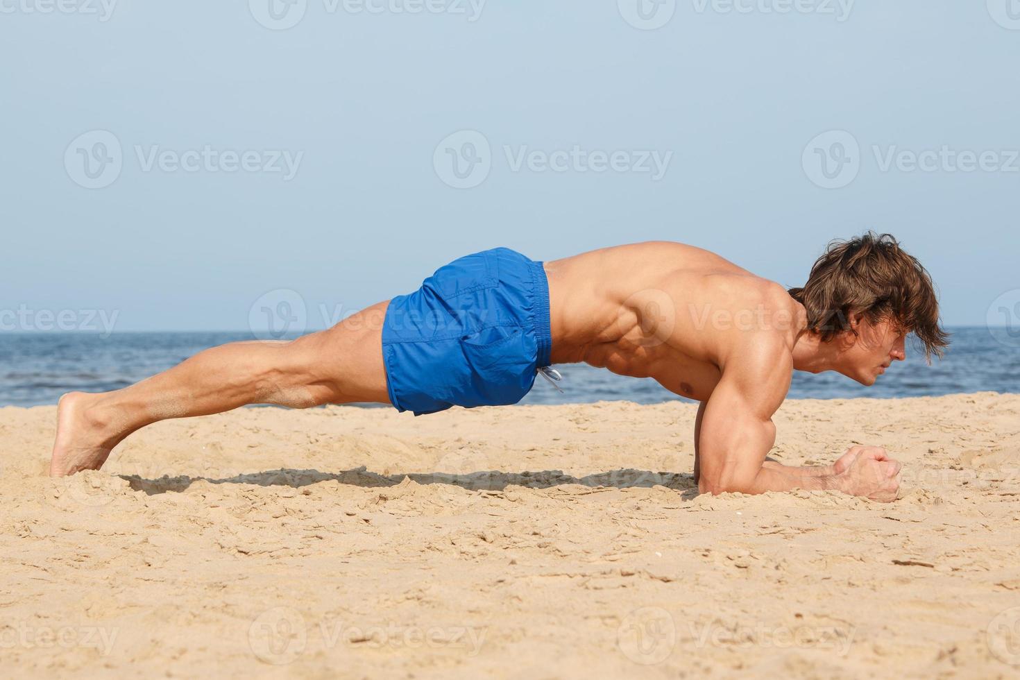 Muscular man during his workout on the beach photo