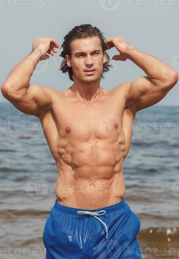 Muscular man during his workout on the beach photo