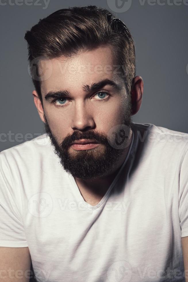 Portrait of young handsome bearded man in studio photo