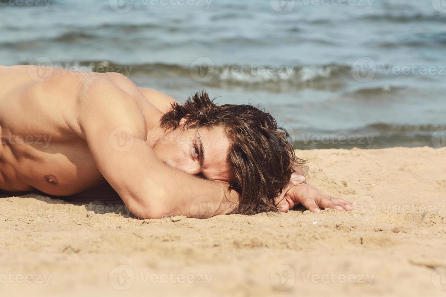 Muscular man during his workout on the beach photo