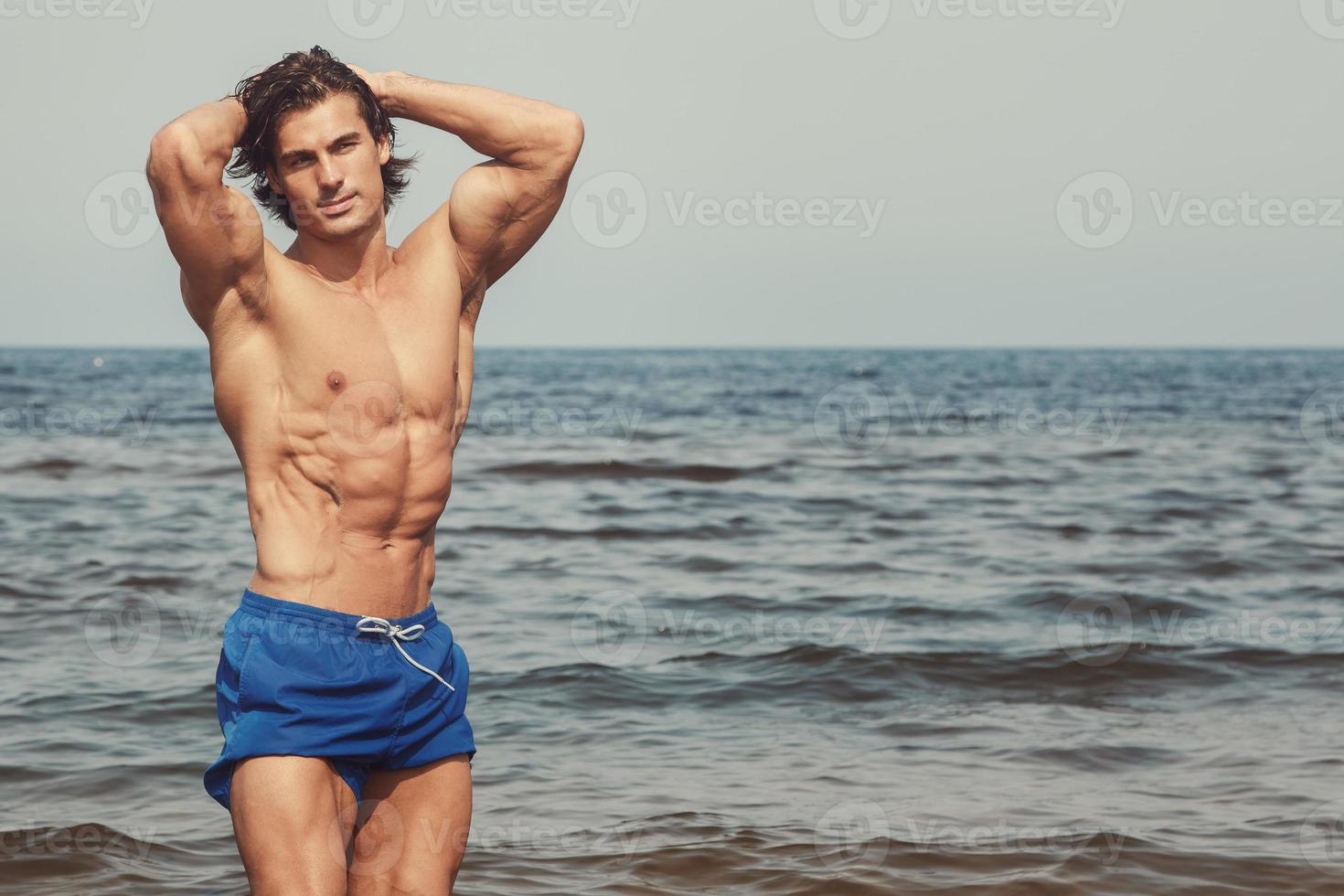 Muscular man during his workout on the beach photo