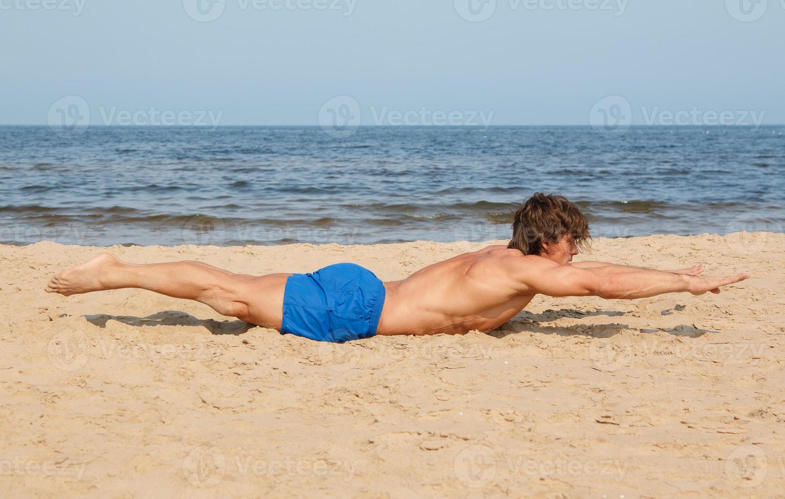 Muscular man during his workout on the beach photo