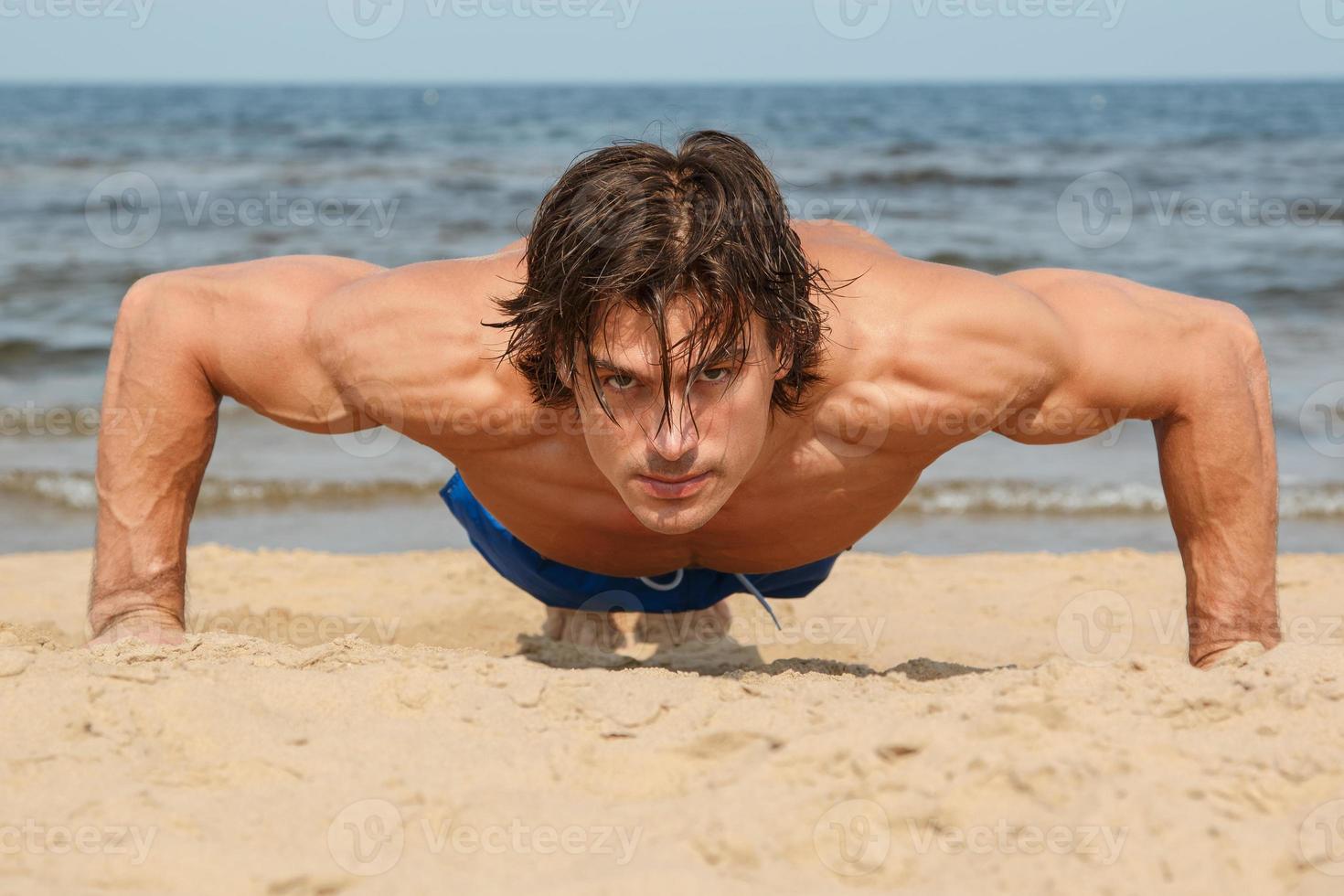 Muscular man during his workout on the beach photo