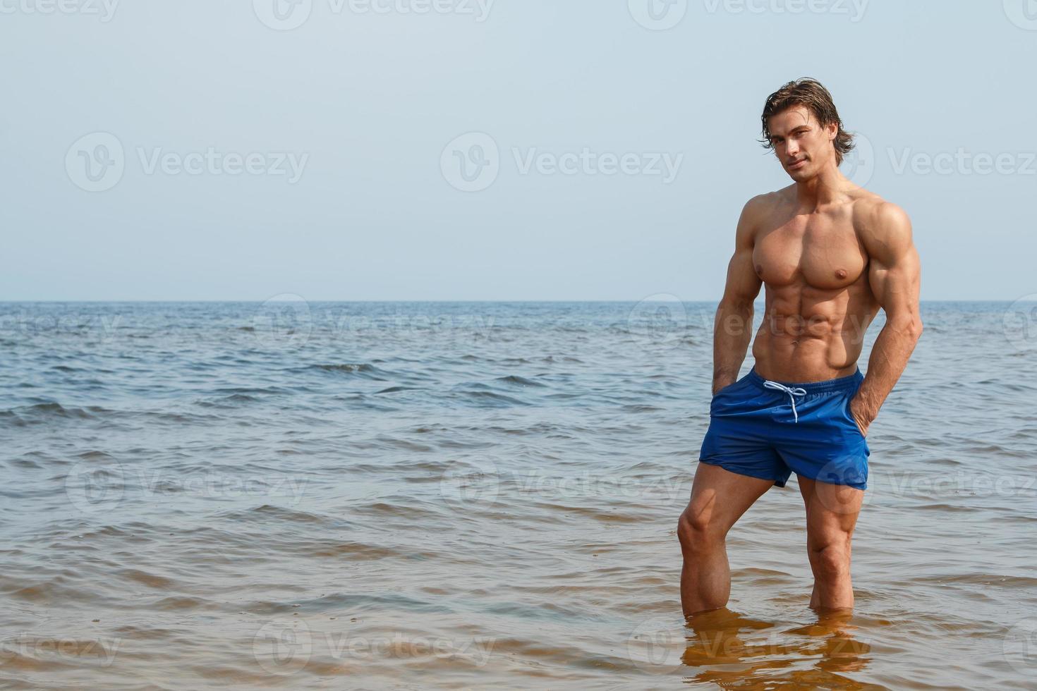 Muscular man during his workout on the beach photo