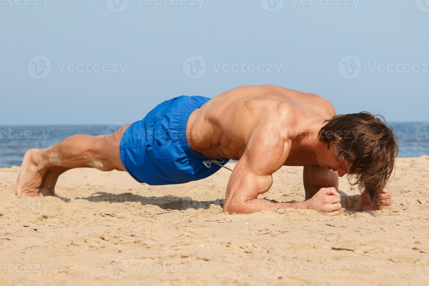 Muscular man during his workout on the beach photo