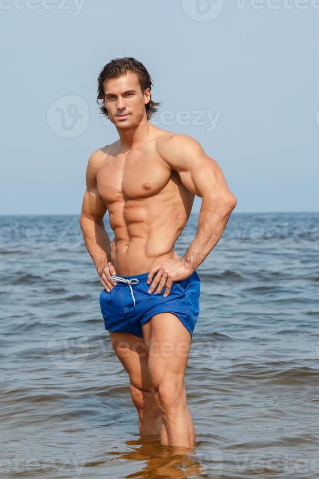 Muscular man during his workout on the beach photo