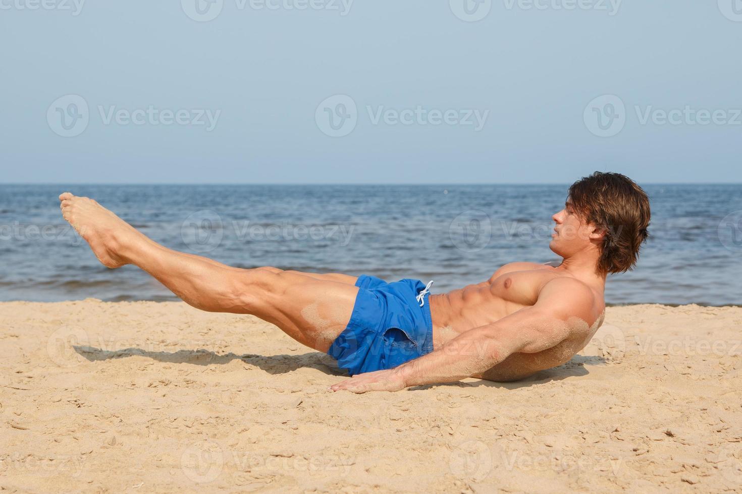 Muscular man during his workout on the beach photo