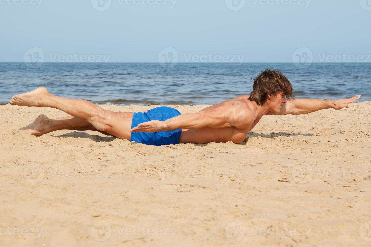 Muscular man during his workout on the beach photo