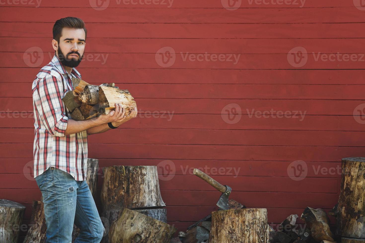 Portrait of handsome bearded man holding firewoods photo