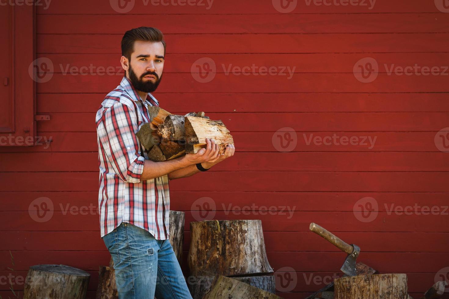 Portrait of Handsome bearded man holding firewoods photo