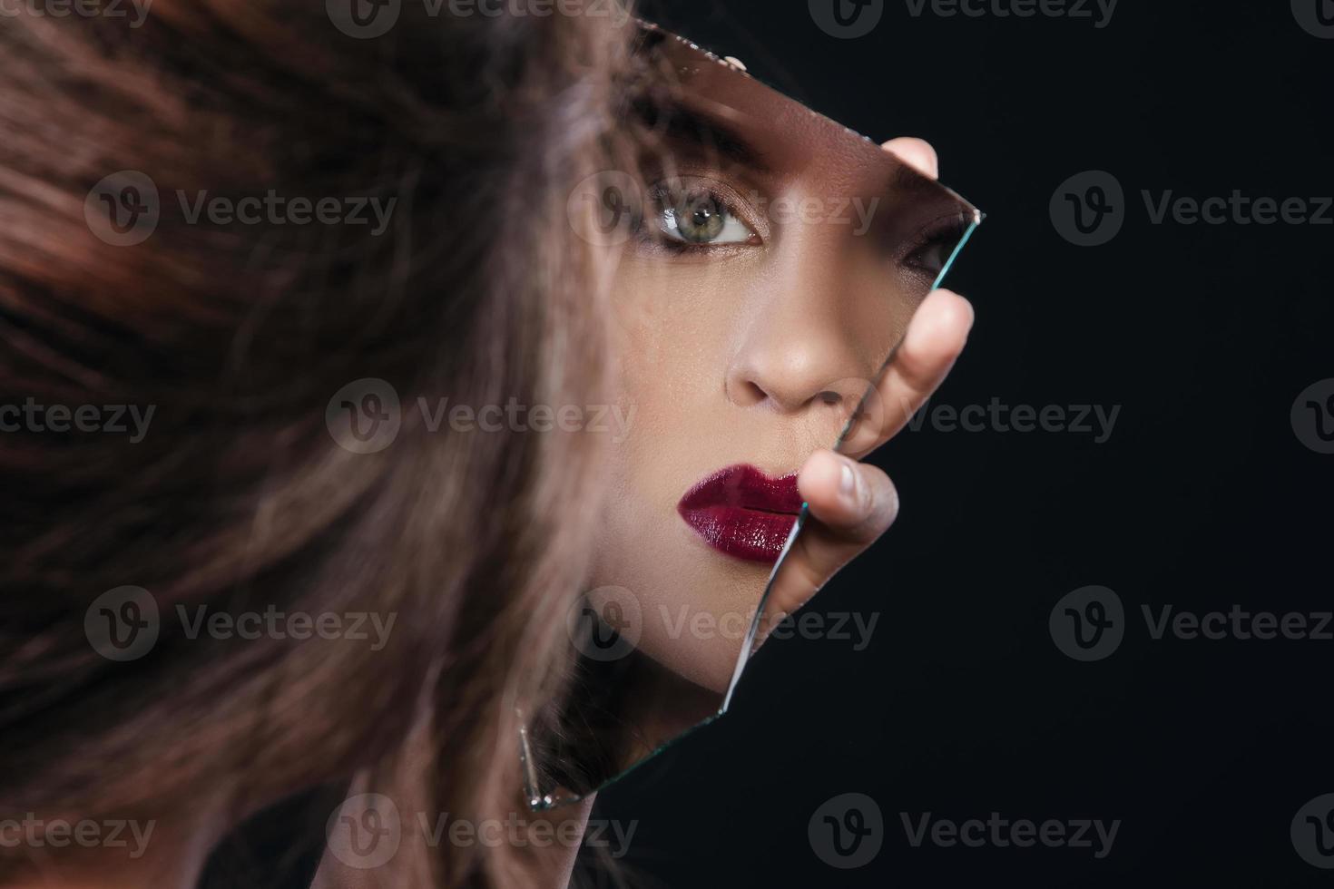 Woman looking in the piece of mirror photo