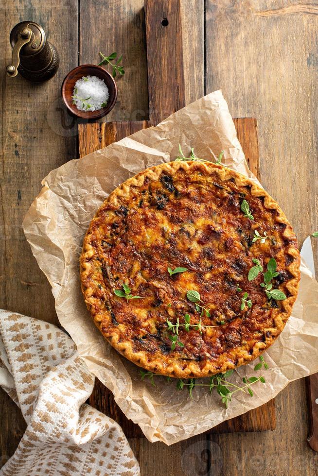 Bacon, mushroom and spinach quiche with cheese and herbs photo