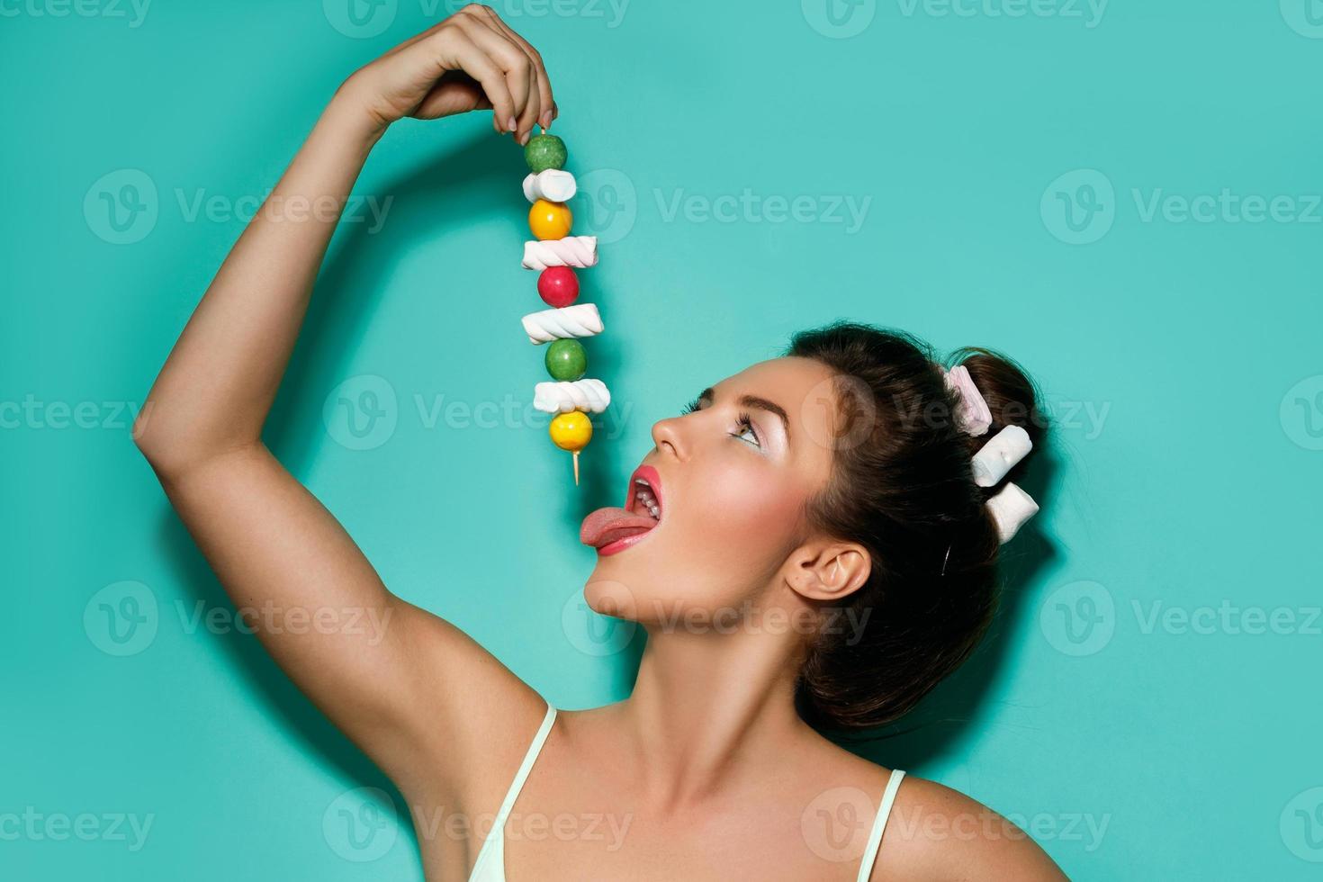 Happy woman with colorful makeup and sweet candies on skewer photo