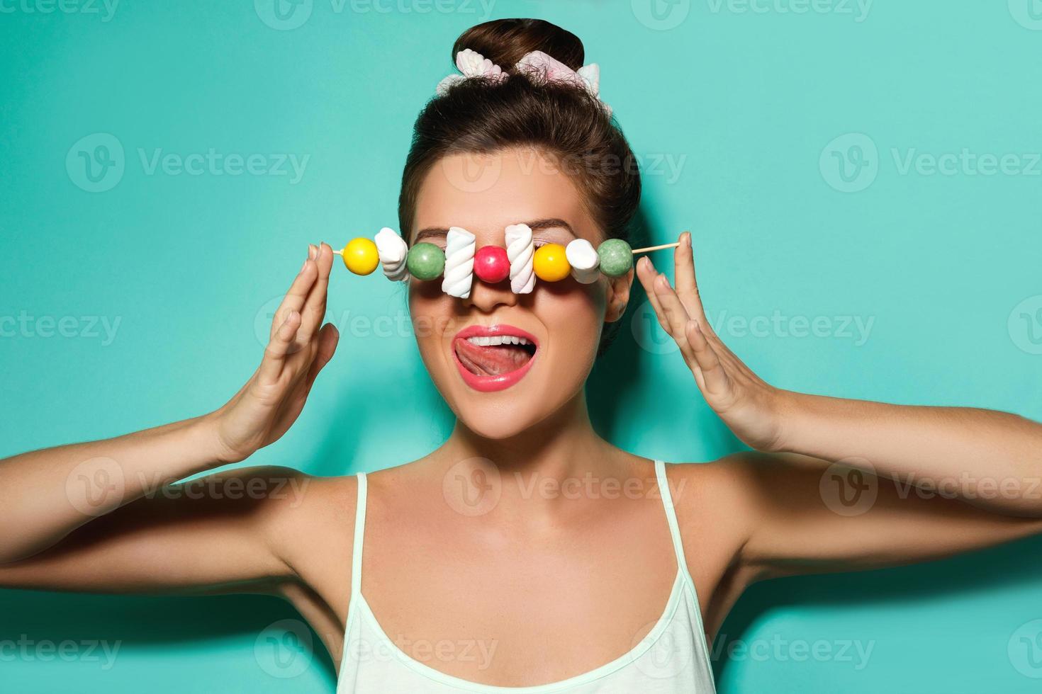Happy woman with colorful makeup and sweet candies on skewer photo