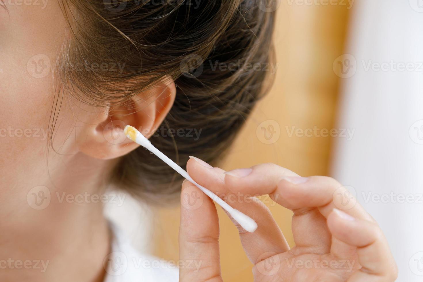 mujer limpiando la oreja con un hisopo de algodón foto