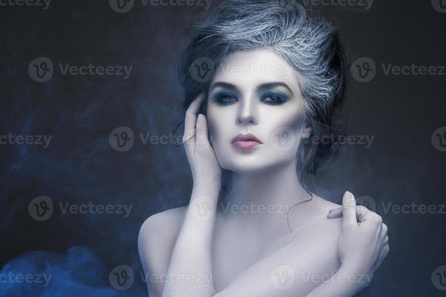 Woman in white body-art in creative image of winter, snow queen, or another sad or evil character photo