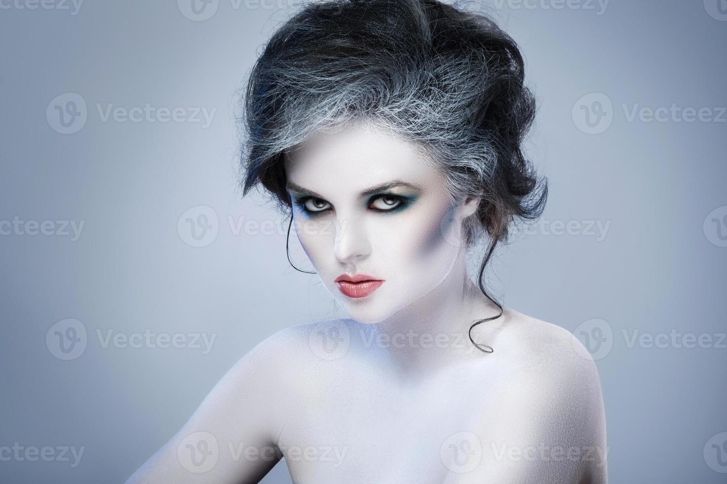 Woman in white body-art in creative image of winter, snow queen, or another sad or evil character photo