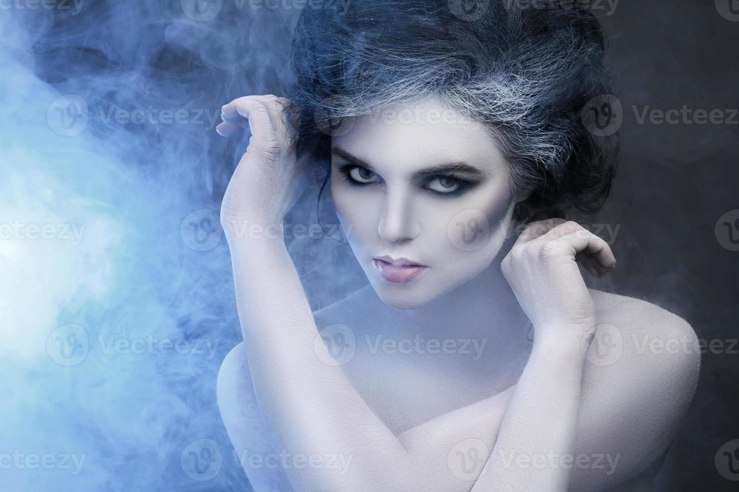 Woman in white body-art in creative image of winter, snow queen, or another sad or evil character photo