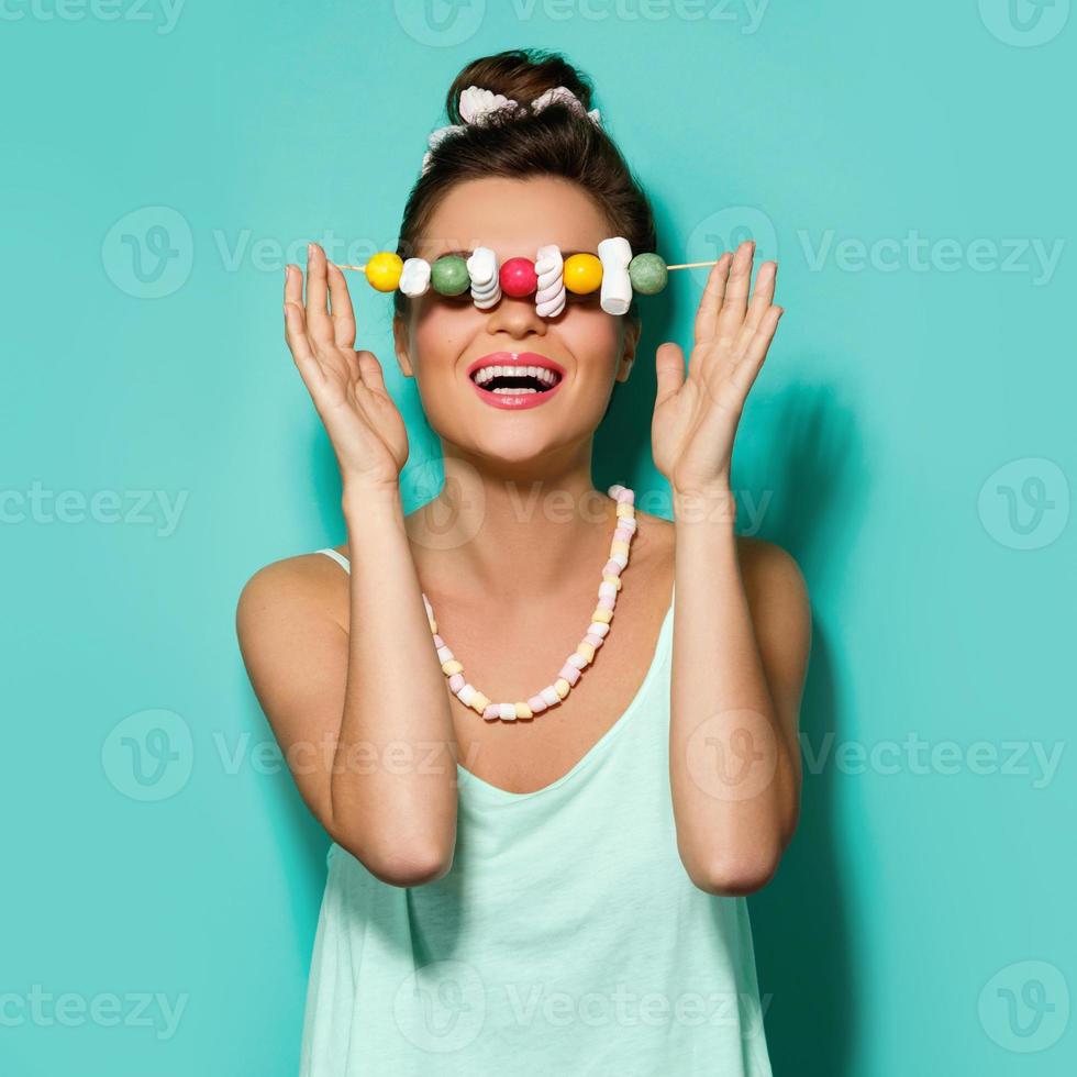 Happy woman with colorful makeup and sweet candies on skewer photo