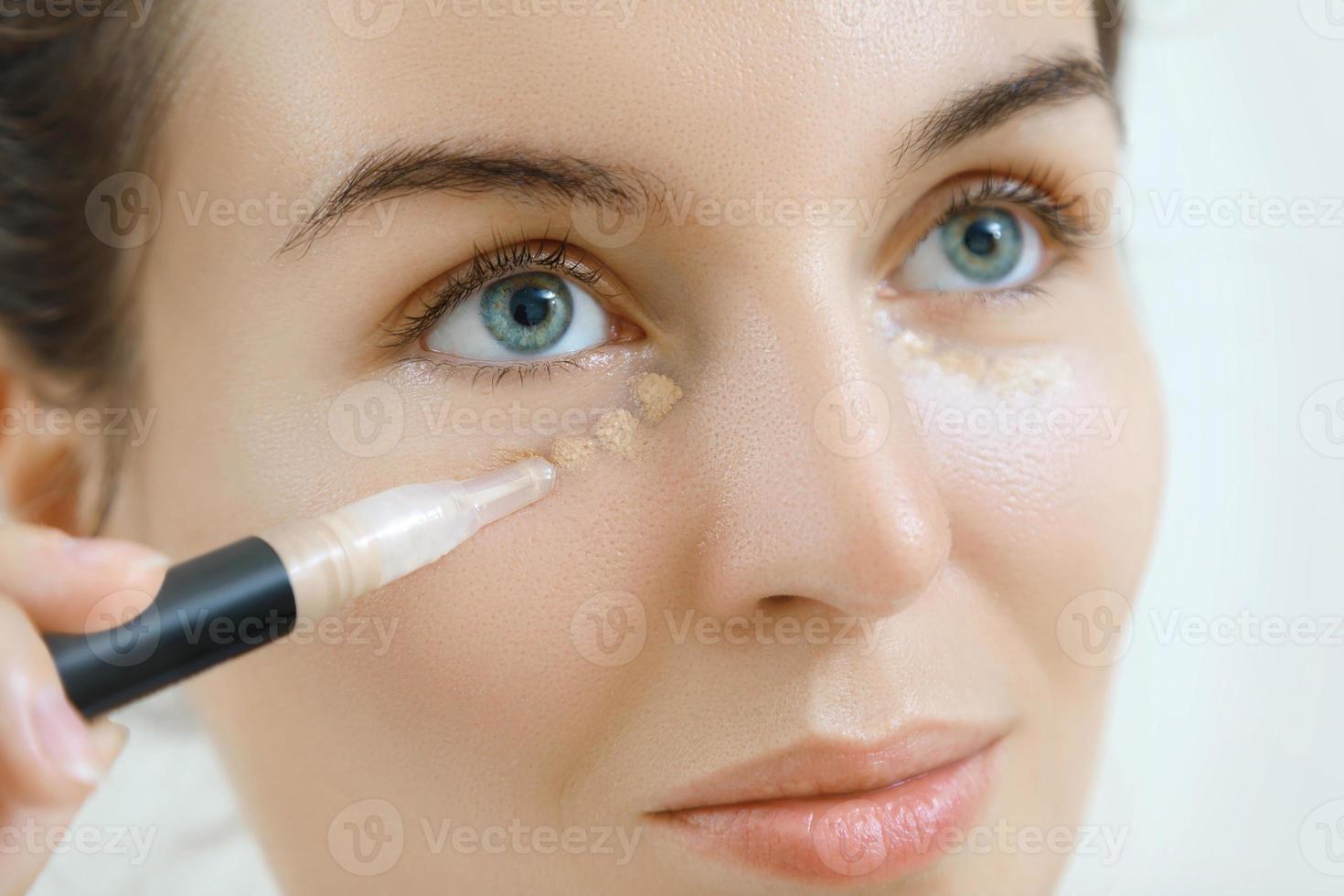 Woman using concealer for under eye circles photo