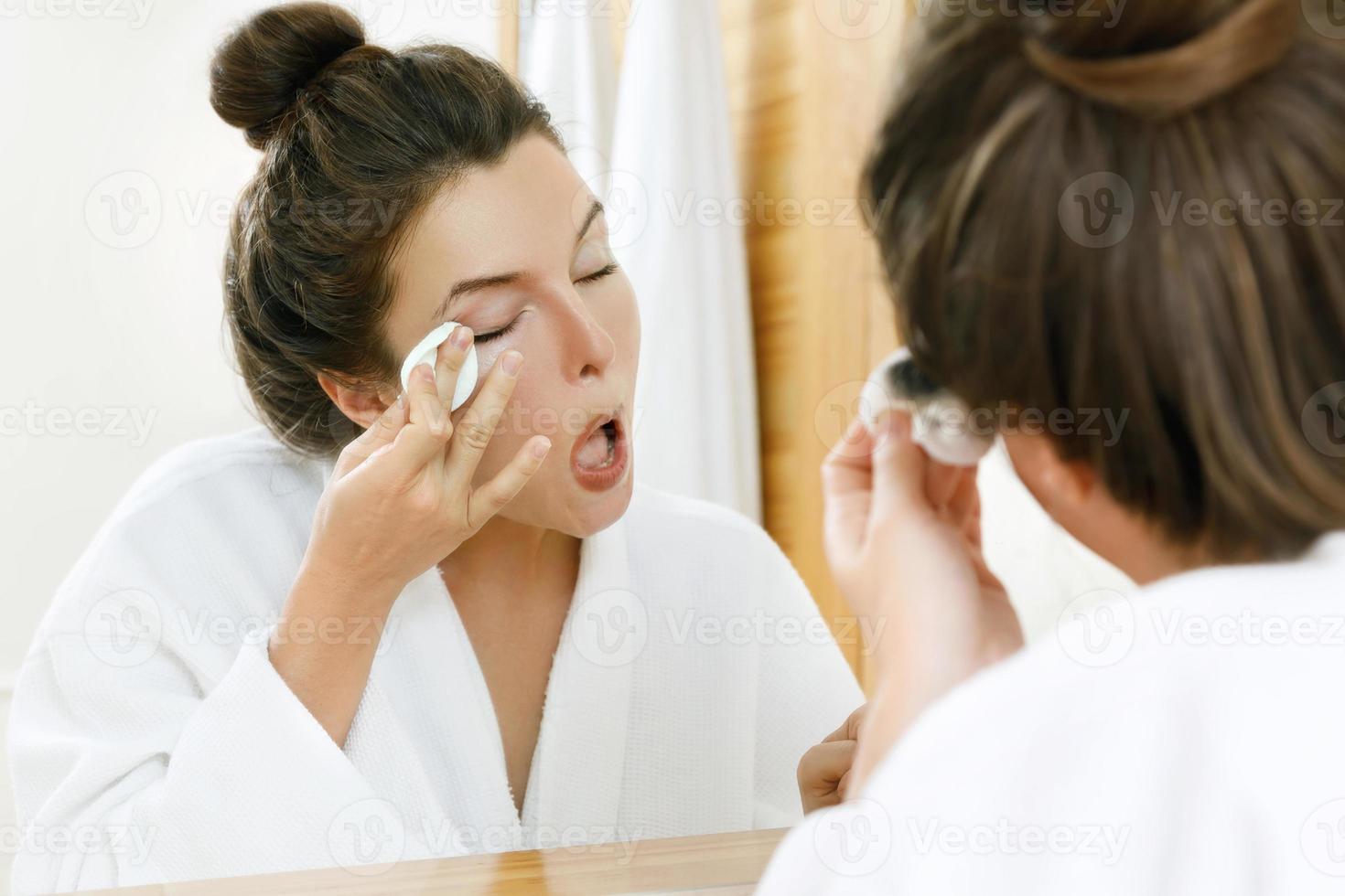 Woman is removing makeup with a cotton pad photo