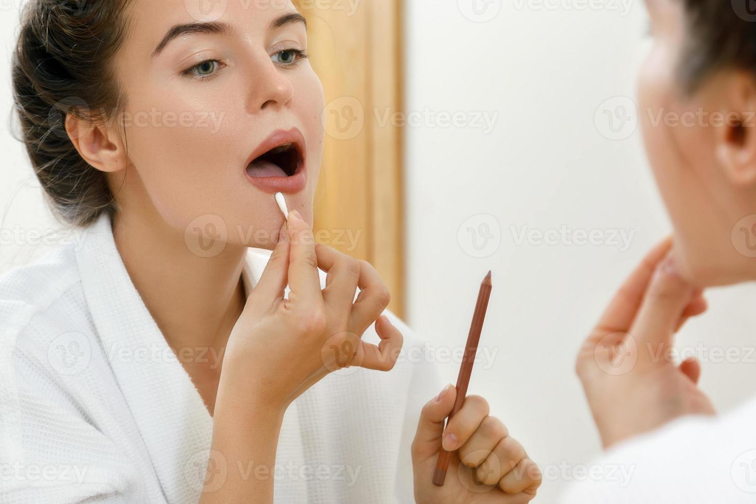 Woman drawing lip contour with a pencil photo