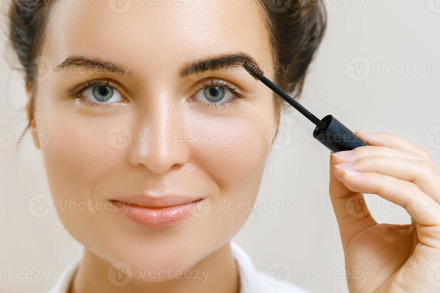 Beautiful woman is applying tinted eyebrow gel photo