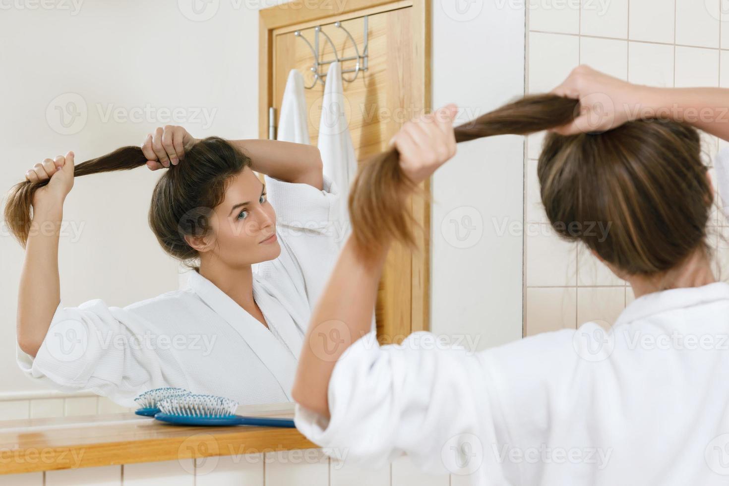 Woman with a beautiful strong hair looking into the mirror photo