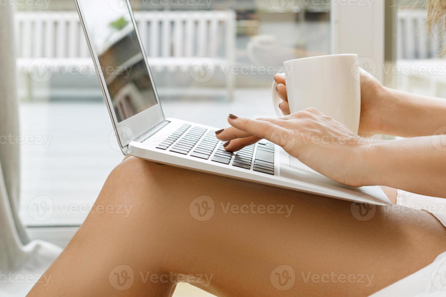 Woman is using laptop pc and drinking coffee photo
