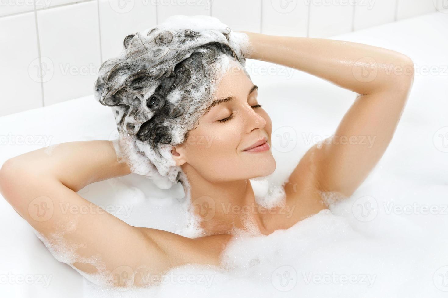 Woman is washing her hair with shampoo photo