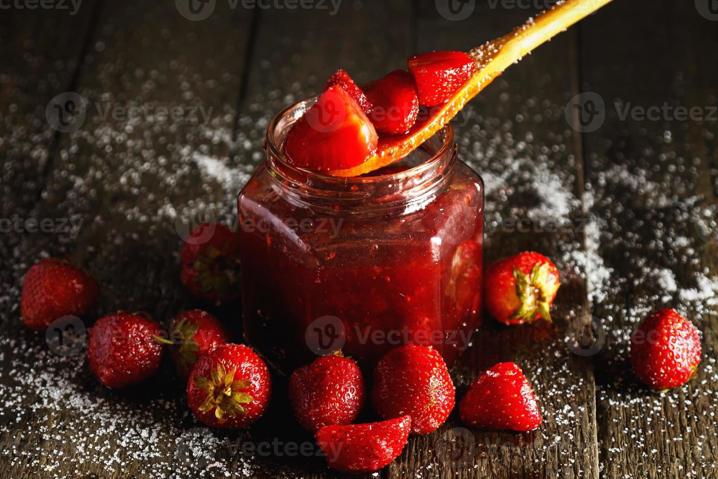 Homemade sweet strawberry jam on wooden table photo