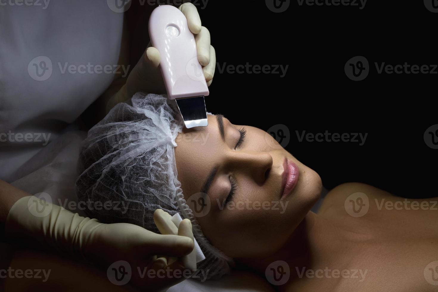 mujer en un salón de spa de belleza profesional durante el procedimiento de limpieza facial ultrasónica foto