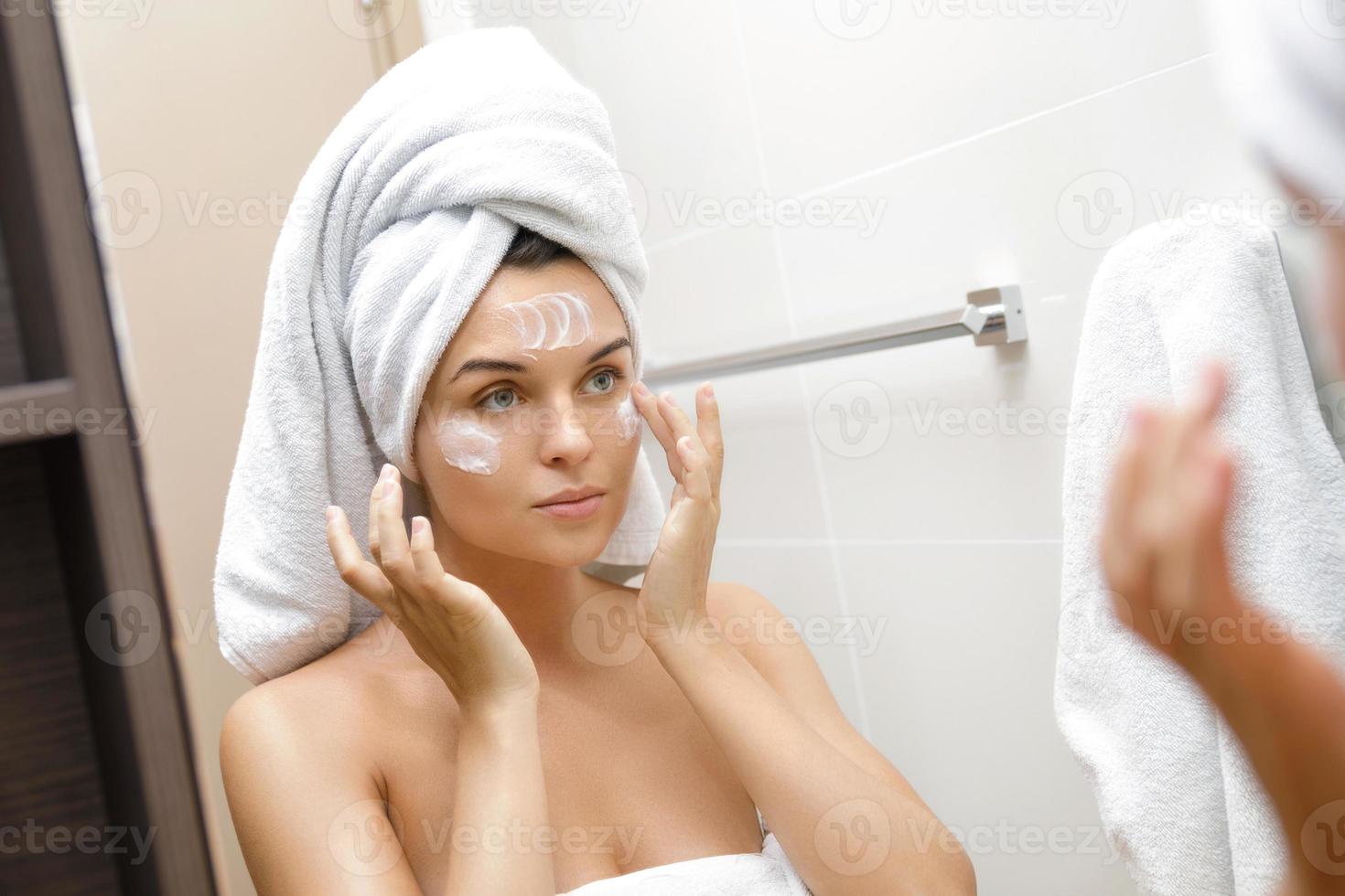 Young woman with moisturizing and anti-aging cream applied on her face photo