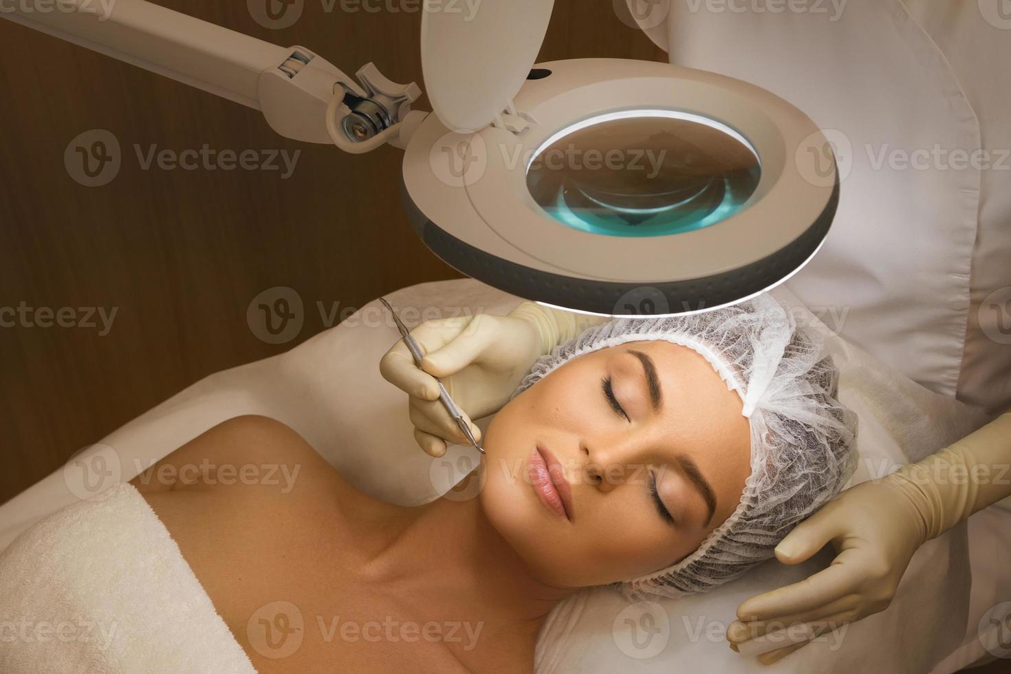 Woman during a mechanical face cleansing procedure photo