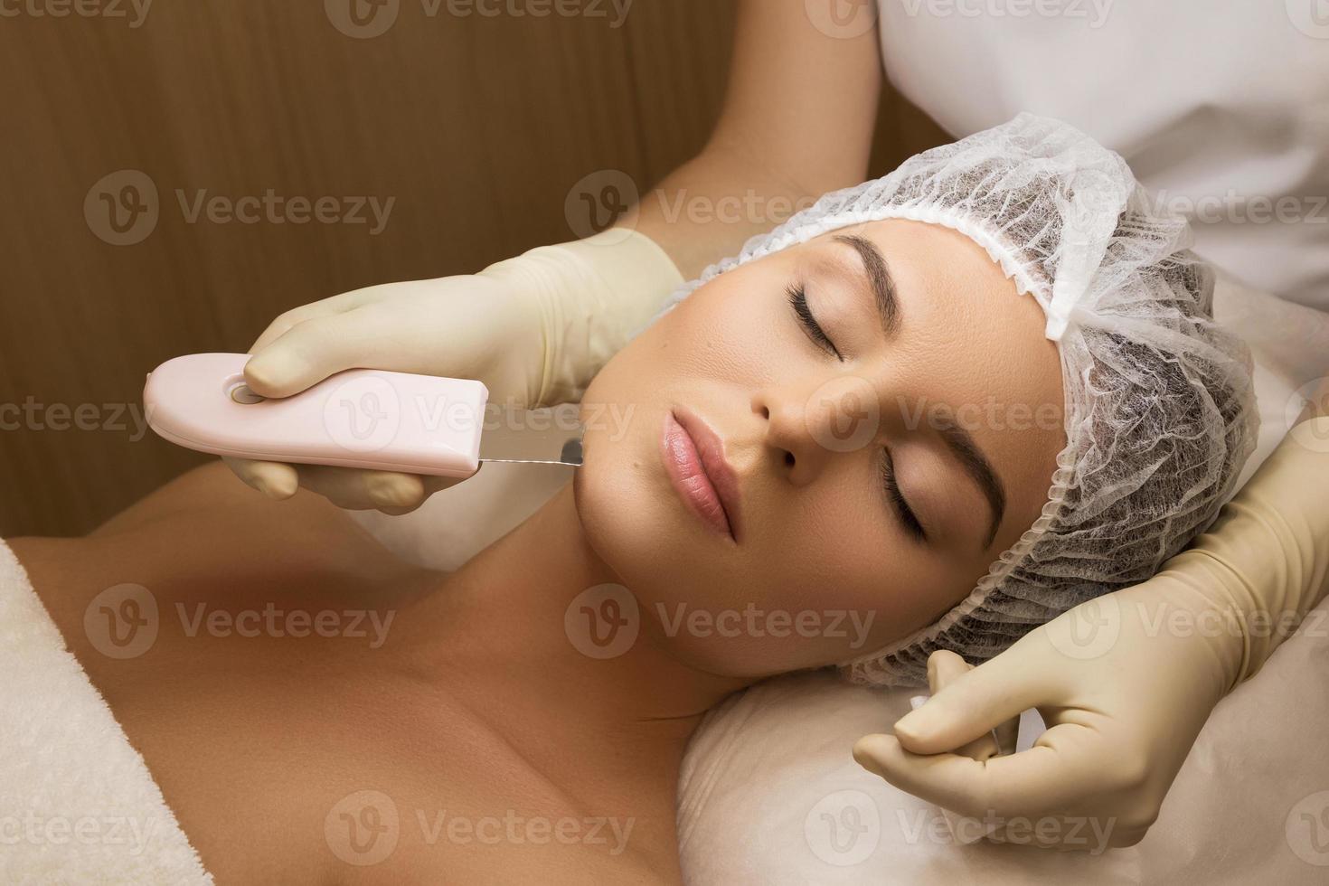 Woman in professional beauty spa salon during ultrasonic facial cleansing procedure photo