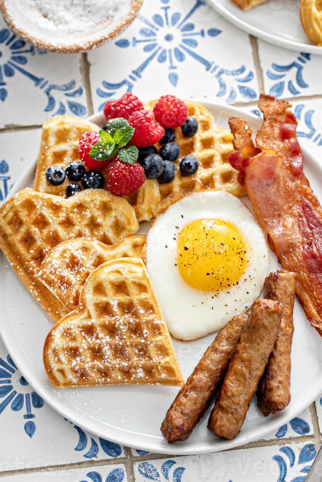 mesa de desayuno con gofres. huevo frito, bacon y salchicha foto